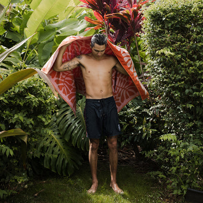 Jacquard beach towel with textured pattern in a tropical garden setting.