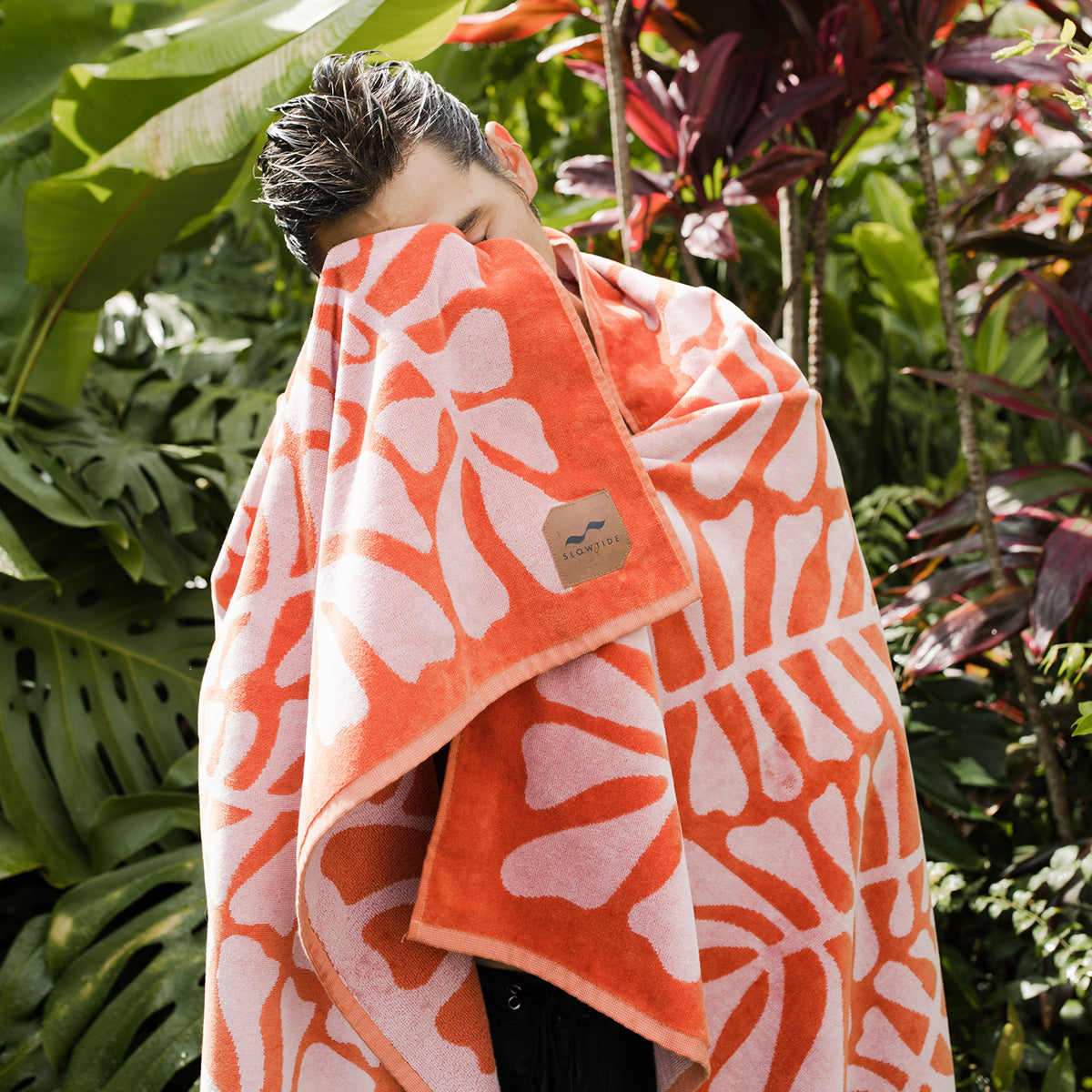 Jacquard beach towel in coral and white with geometric pattern, shown wrapped for use.