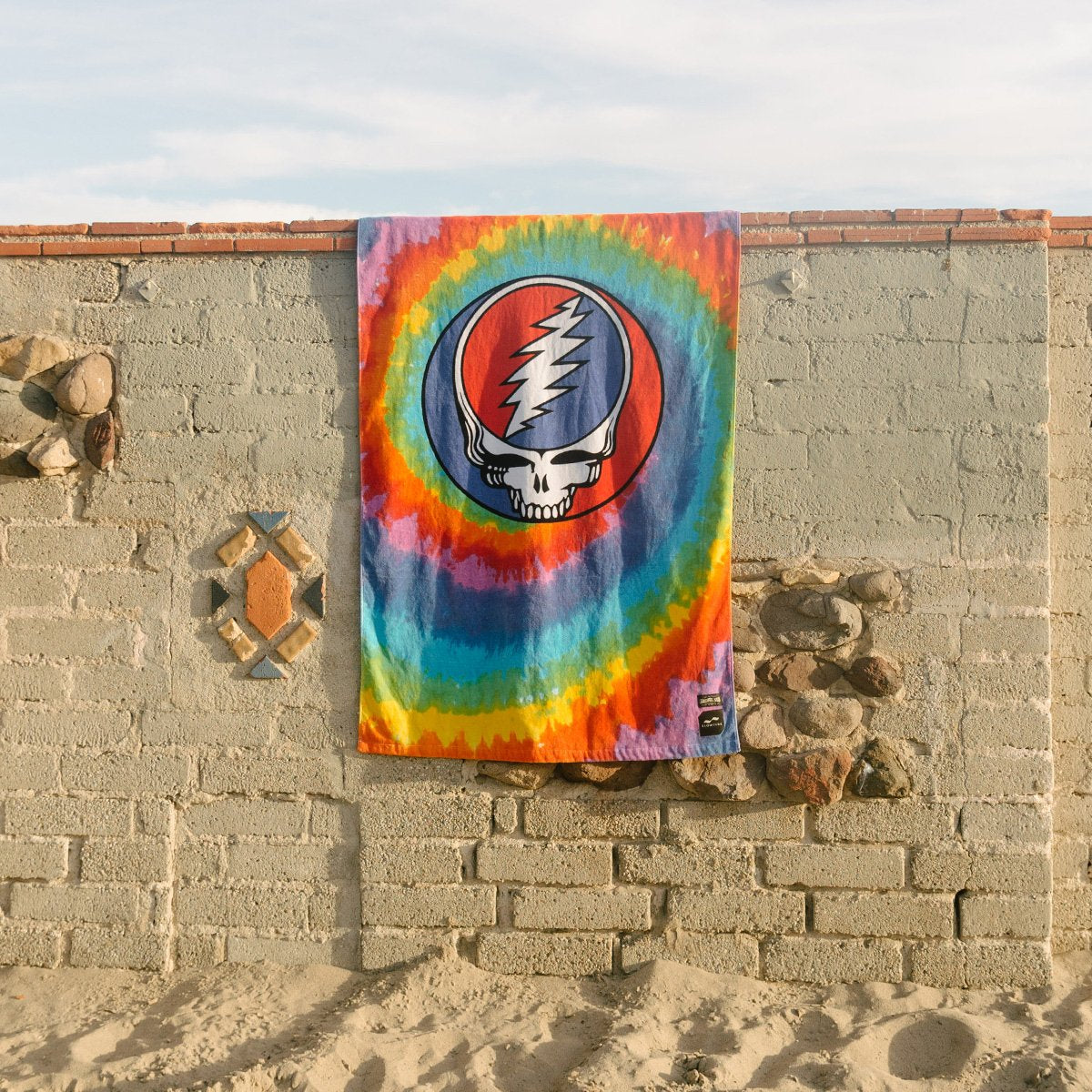 Beach towel, absorbent fabric, skull and lightning bolt print, drying outdoors.
