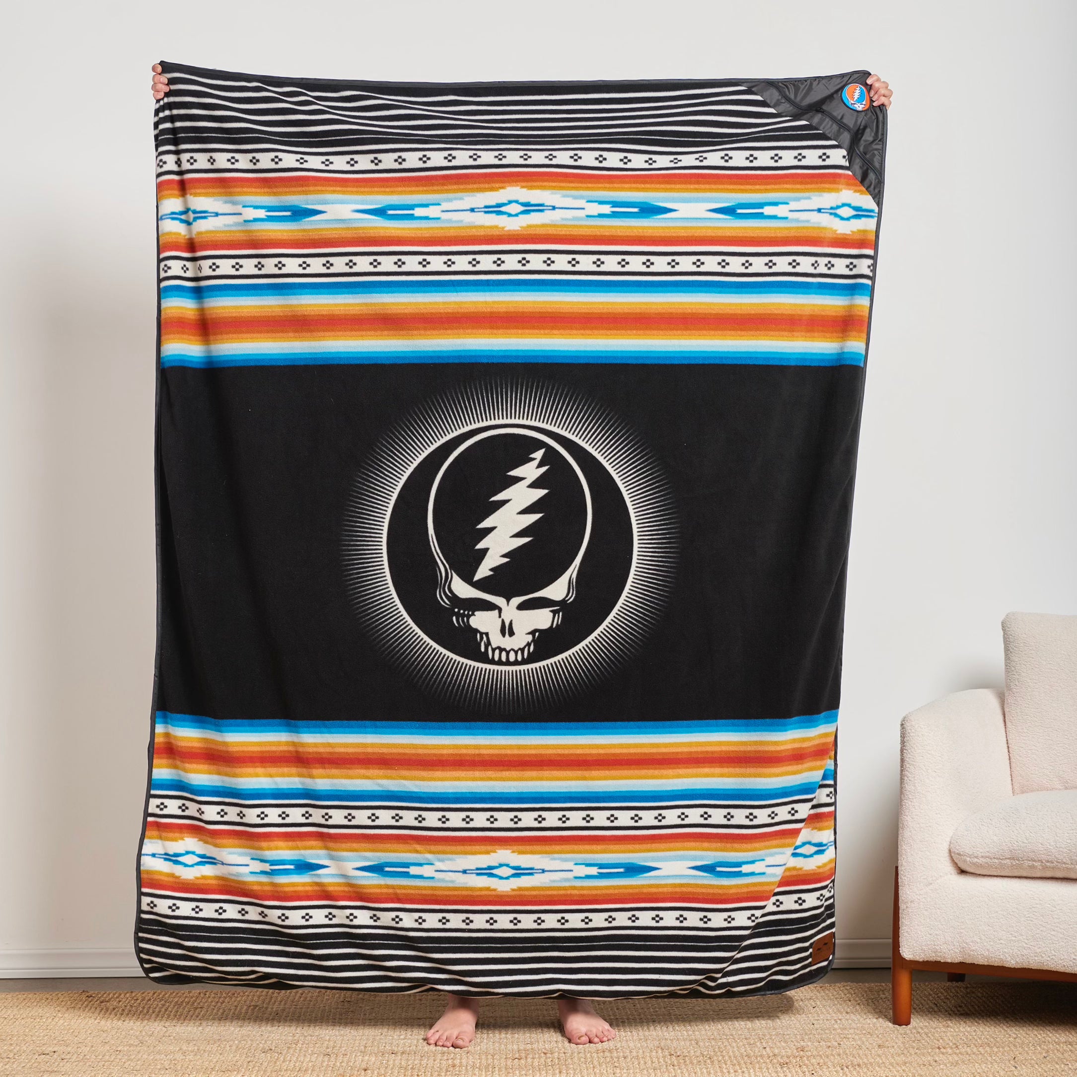 Recycled material blanket with skull logo and colorful geometric patterns.
