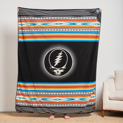Recycled material blanket with skull logo and colorful geometric patterns.
